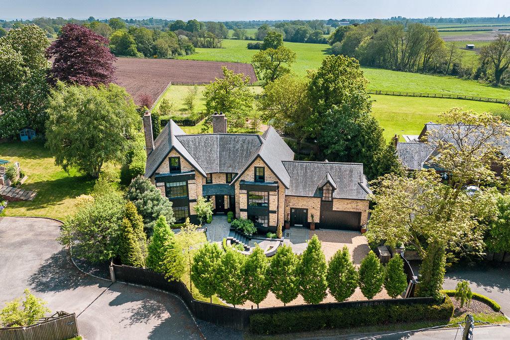Aerial drone view of The Ponds showing the full 0.83-acre plot with house, gardens, ancient oak trees and surrounding countryside