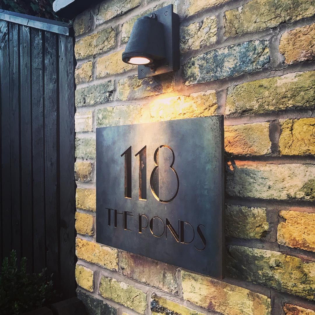 118 The Ponds sign illuminated at night by wall lantern