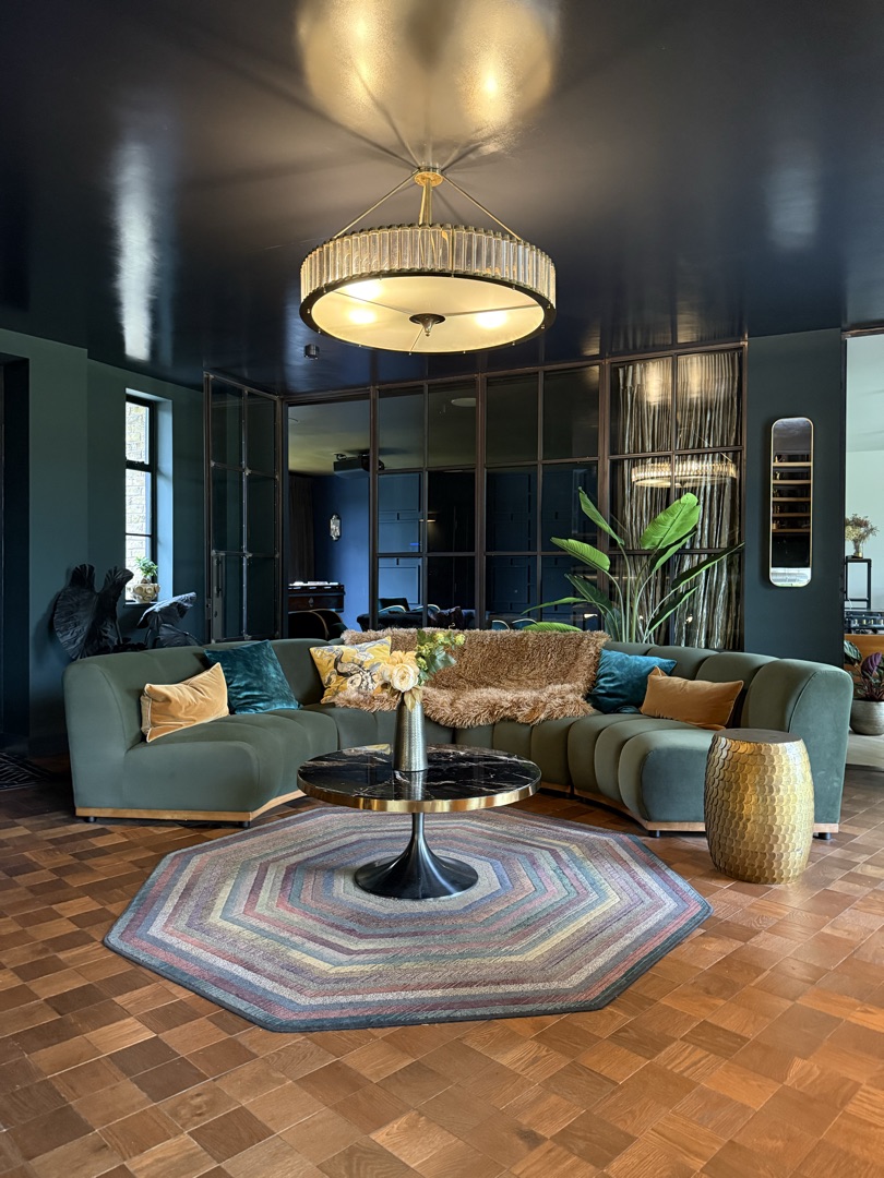 Reception with green velvet curved sofa, art deco chandelier and Crittall garden doors