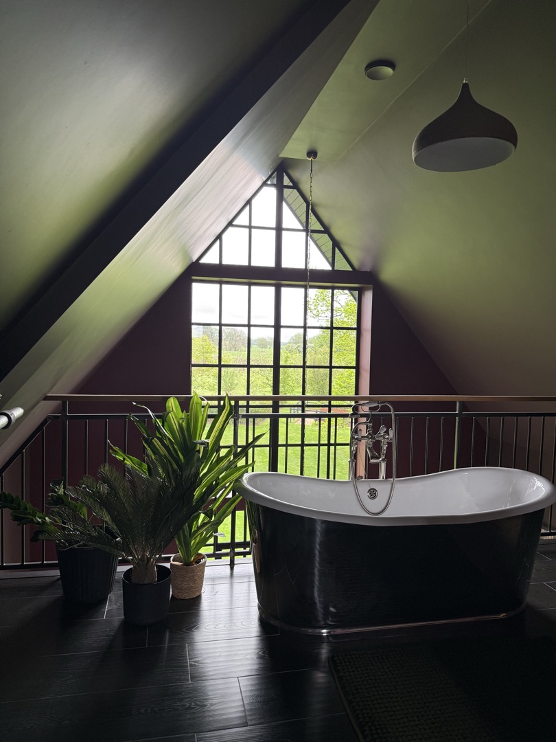 The Ponds Goostrey — polished metal freestanding bath under apex window with countryside views