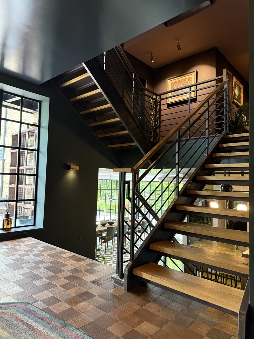 The Ponds Goostrey — stairwell with deep green walls, oak treads and steel balustrading leading down to the dining room