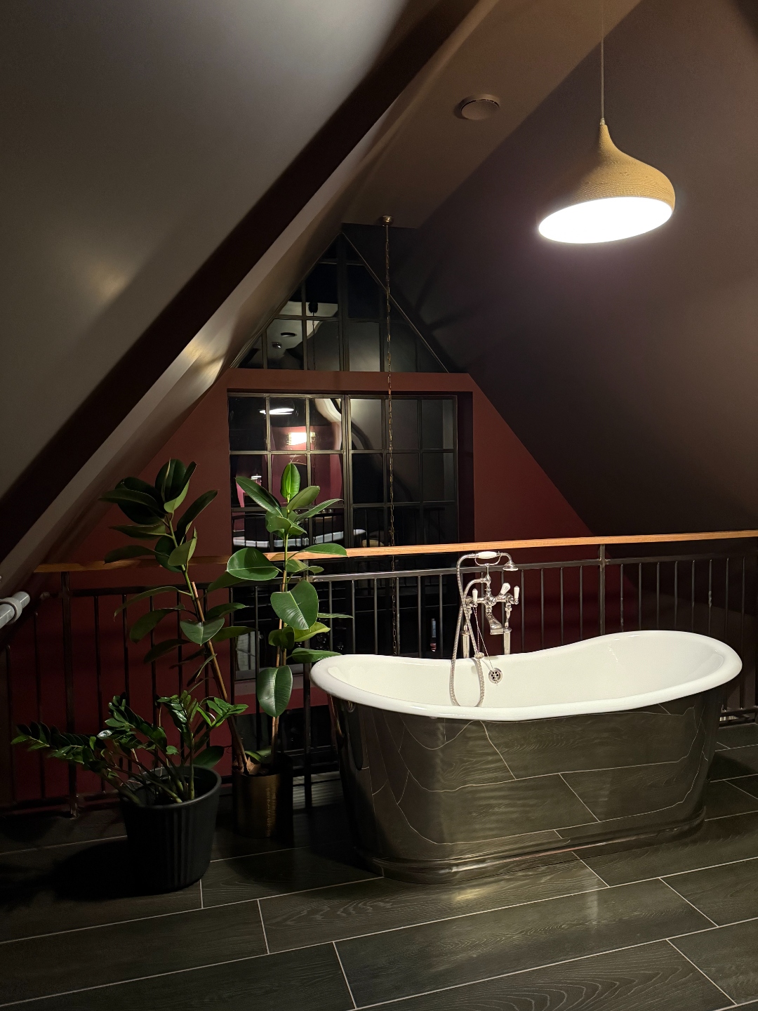 Polished metal freestanding bath on galleried mezzanine overlooking bedroom