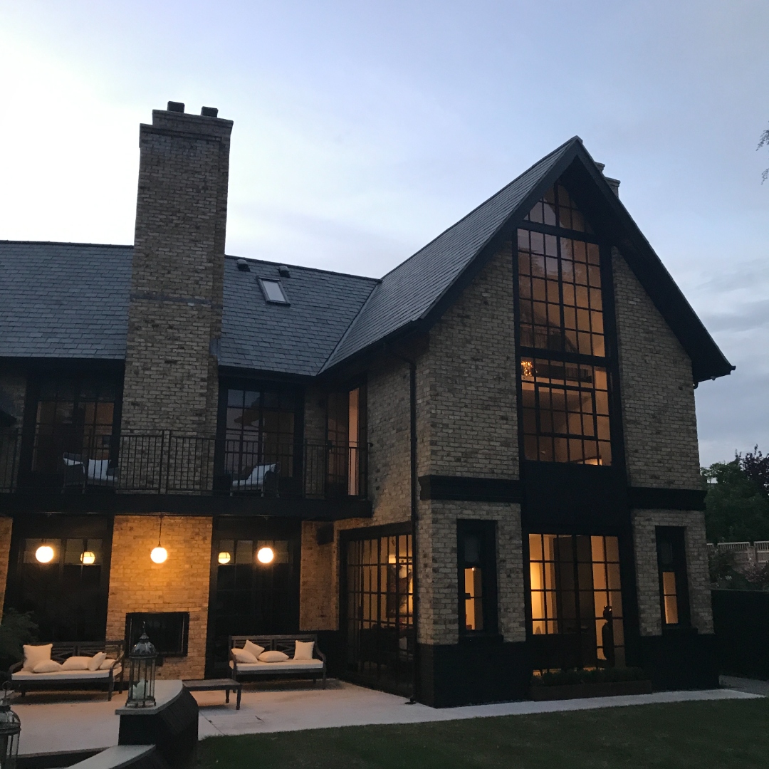 Close-up rear elevation at dusk with outdoor sofas and storm lanterns