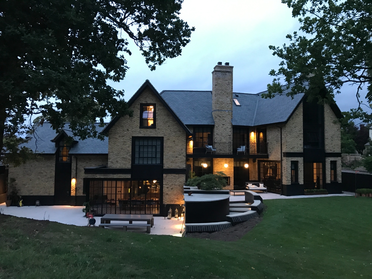 Full rear elevation at dusk with illuminated terrace, hot tub and garden lighting